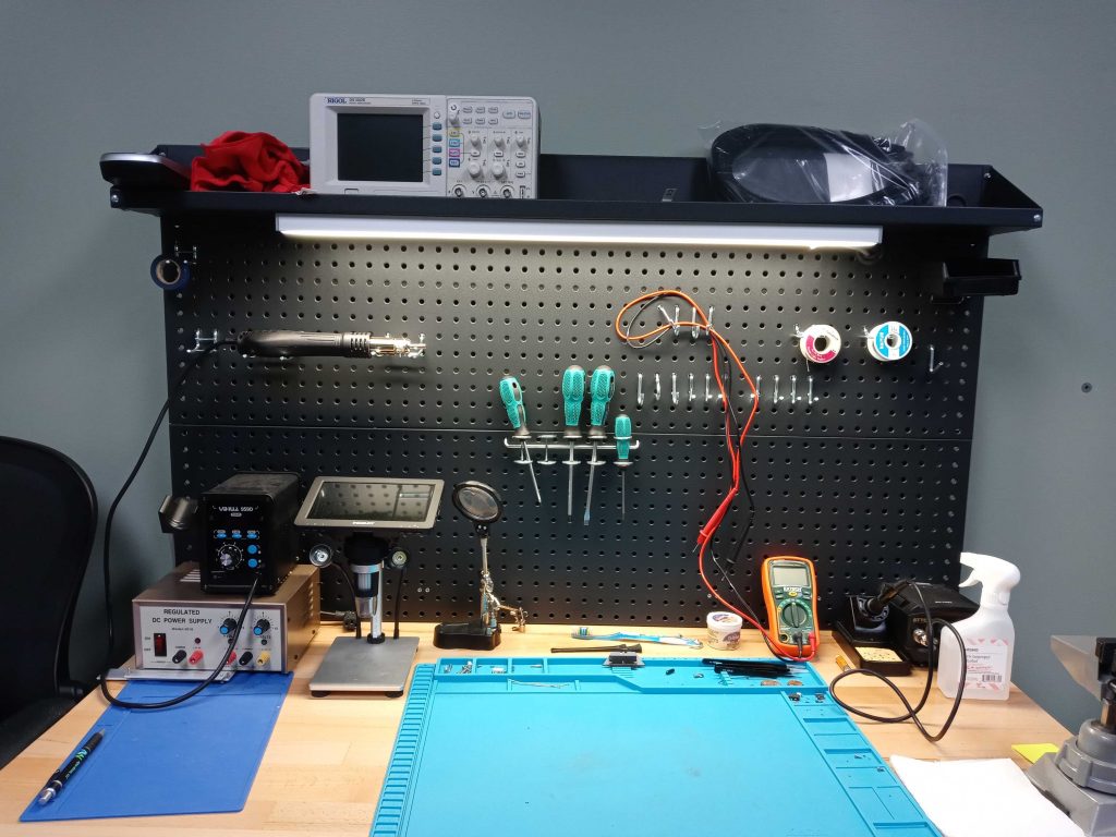 Picture of one of the Apex Waves technician tables, with tools to repair parts and an oscilloscope on the top shelf