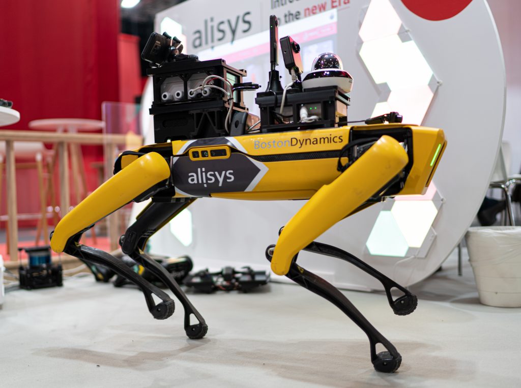 A closeup shot of the Alysis Robot by Boston Dynamics, a four legged yellow robot with incredible balance.