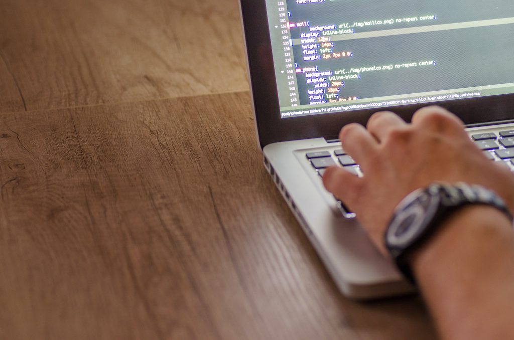 Closeup corner view of man with watch typing on a laptop