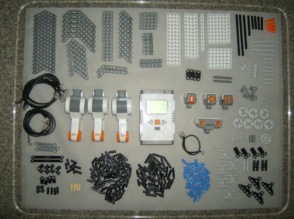 The pieces of a Lego Mindstorms NXT kit, laid out on a table and organized