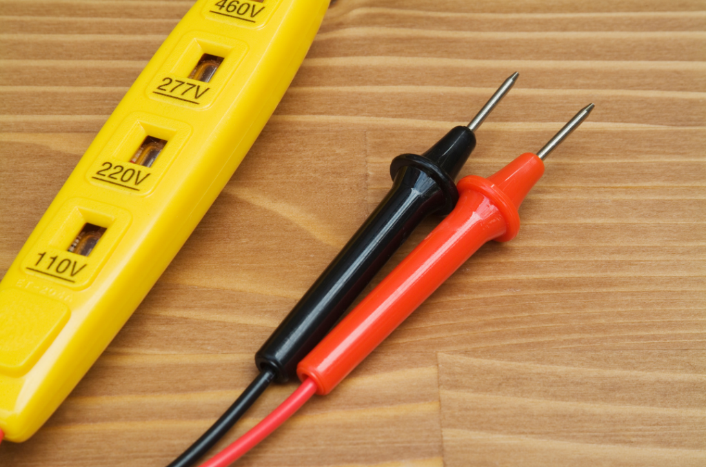 Close up picture of yellow voltmeter with black and red leads