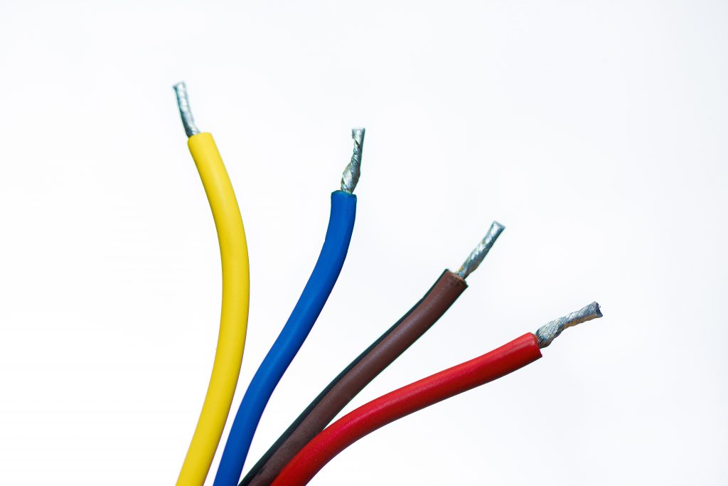 Closeup of a yellow, blue, brown, and red wire with a white background
