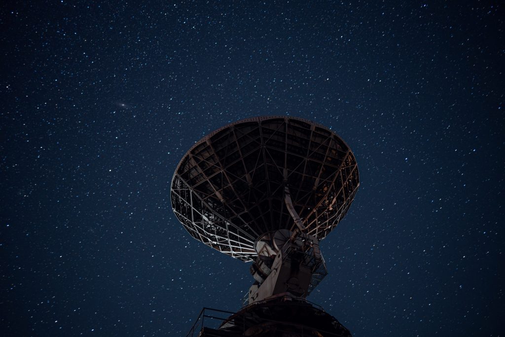 Radar antenna against a starry blue backdrop of the sky at night