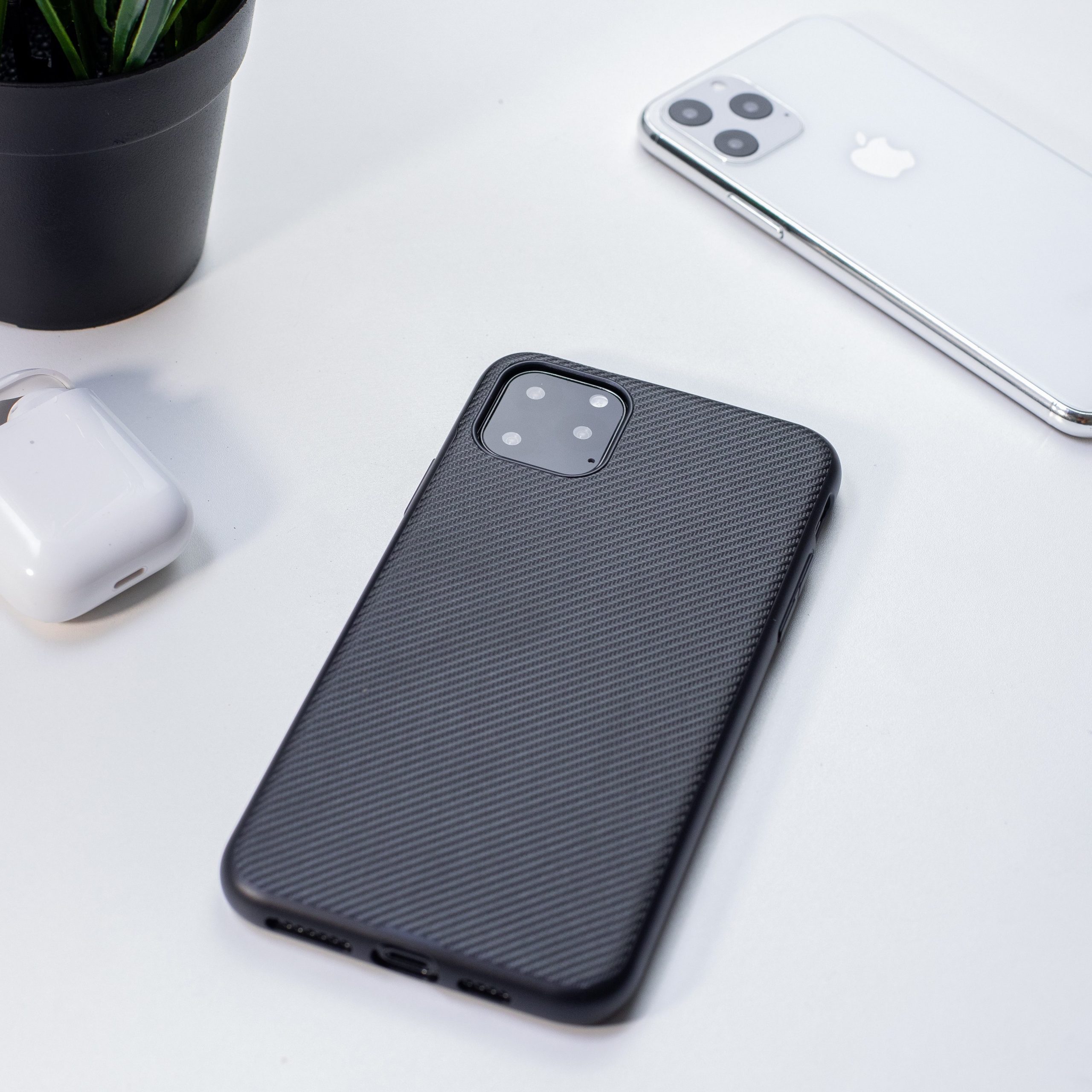 Black and white Iphones laying facedown on a white table