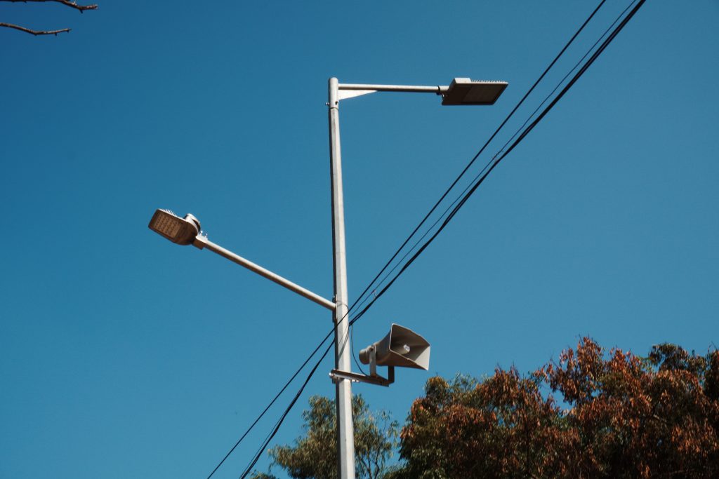 street lamp in India against a blue sky with power lines in the background