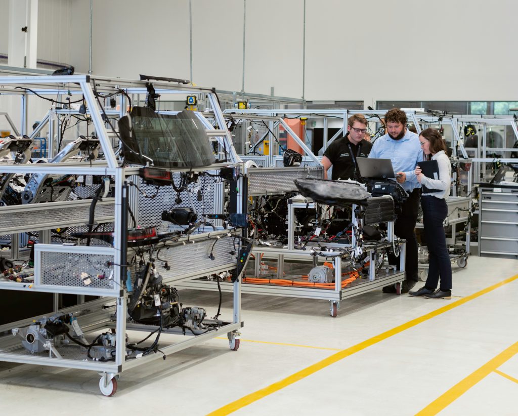 Engineering team of two men and one woman in an automotive manufacturing plant