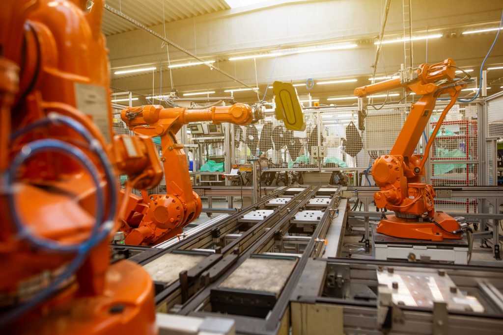 Orange robotic arms in an automotive manufacturing plant