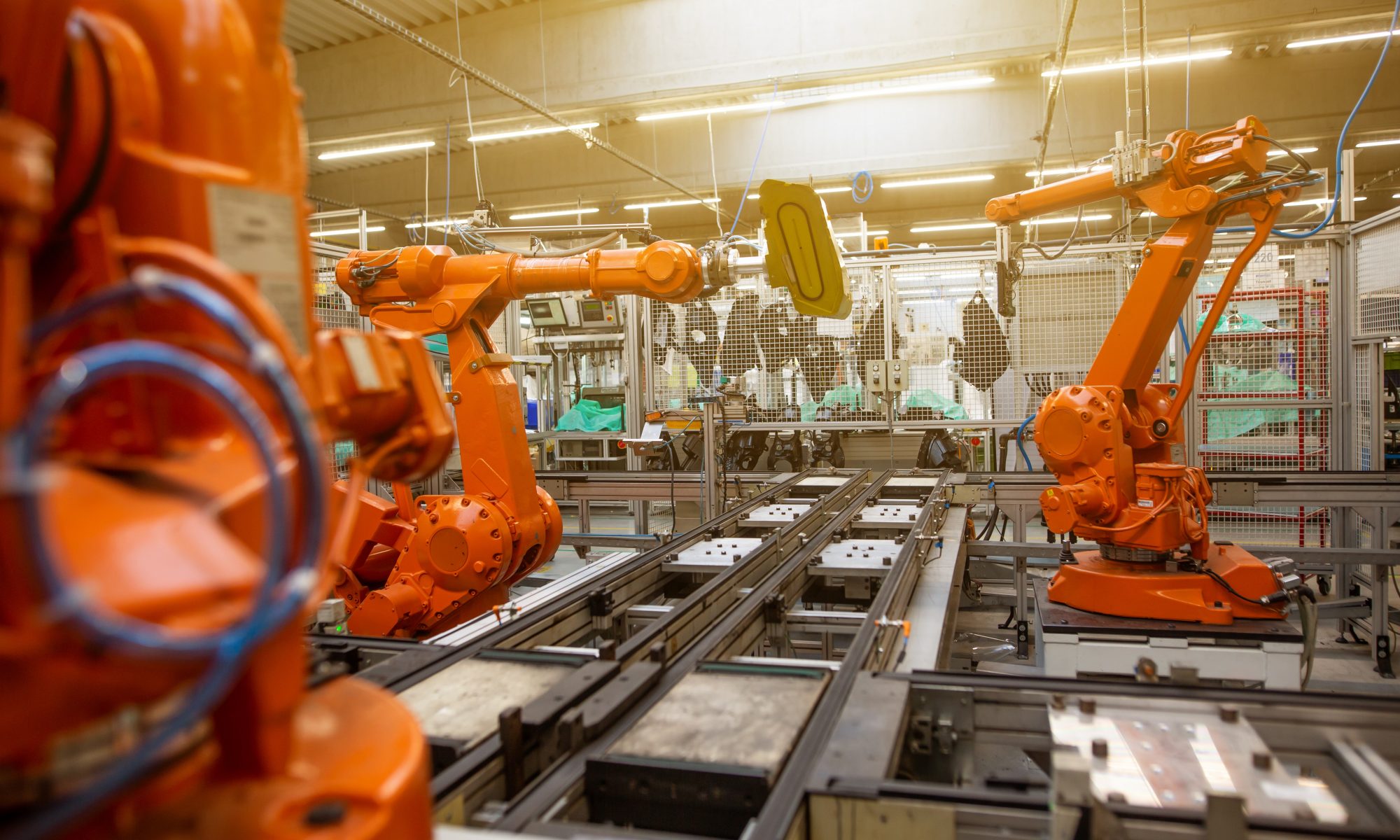 Orange robotic arms in an automotive manufacturing plant