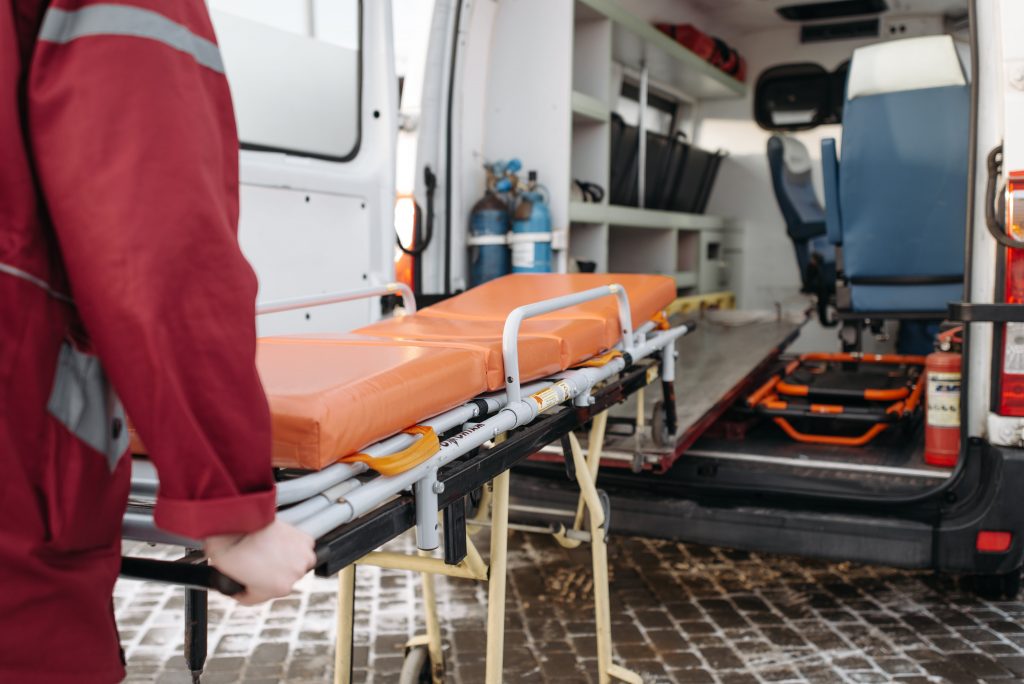 Paramedic getting an orange stretcher out of the back of an ambulance