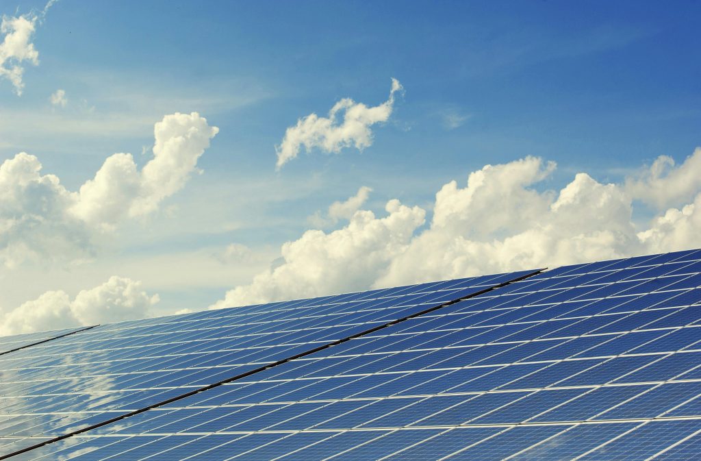 Solar panels with a cloudy blue sky in the background