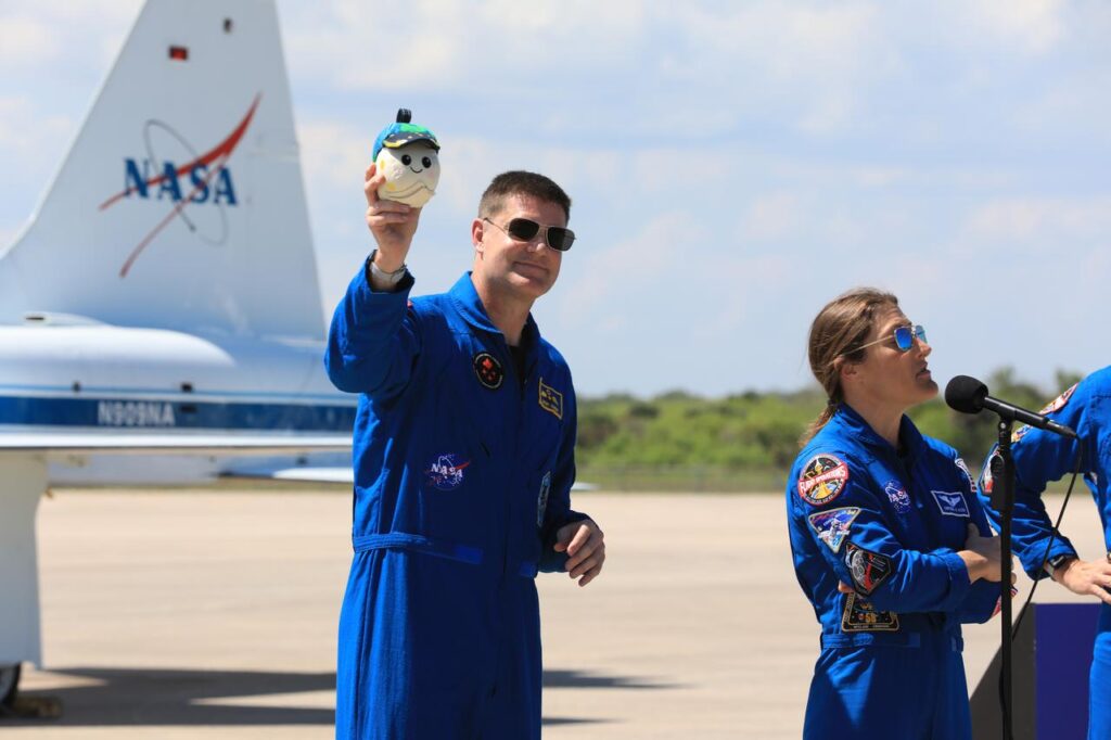 Astronaut Jeremy Hansen holds up the Rise Moon Mascot