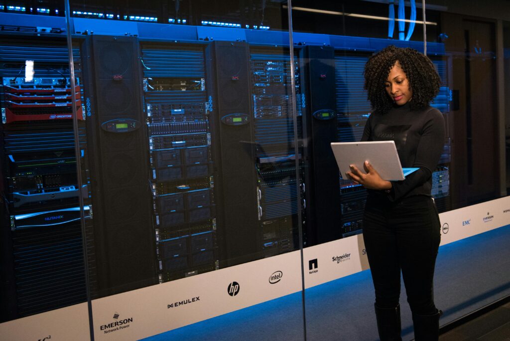 Female engineer standing with a laptop in front of servers in a modern data center.