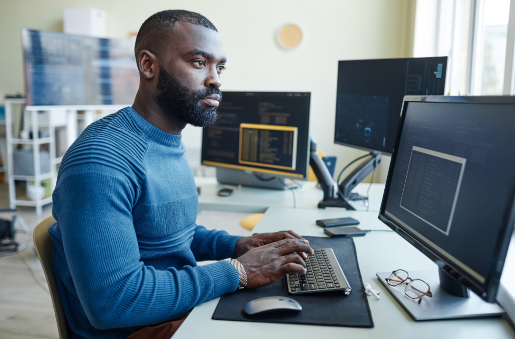 engineer in blue shirt looking at different monitors