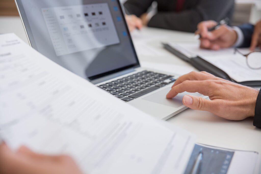 Person looking over document while using laptop